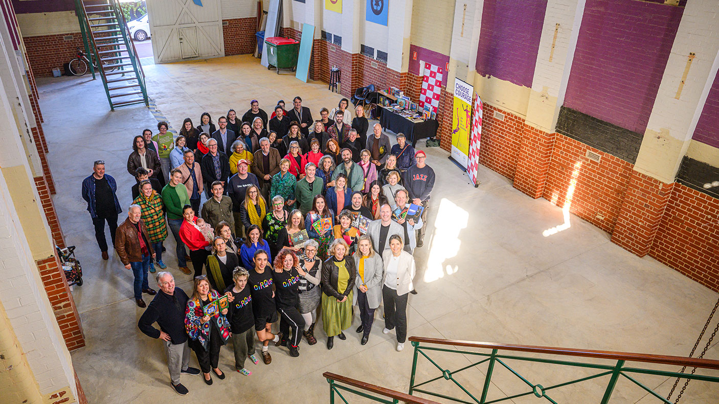 A group of people stand in the old substation building looking up at the photographer who is on a second level.