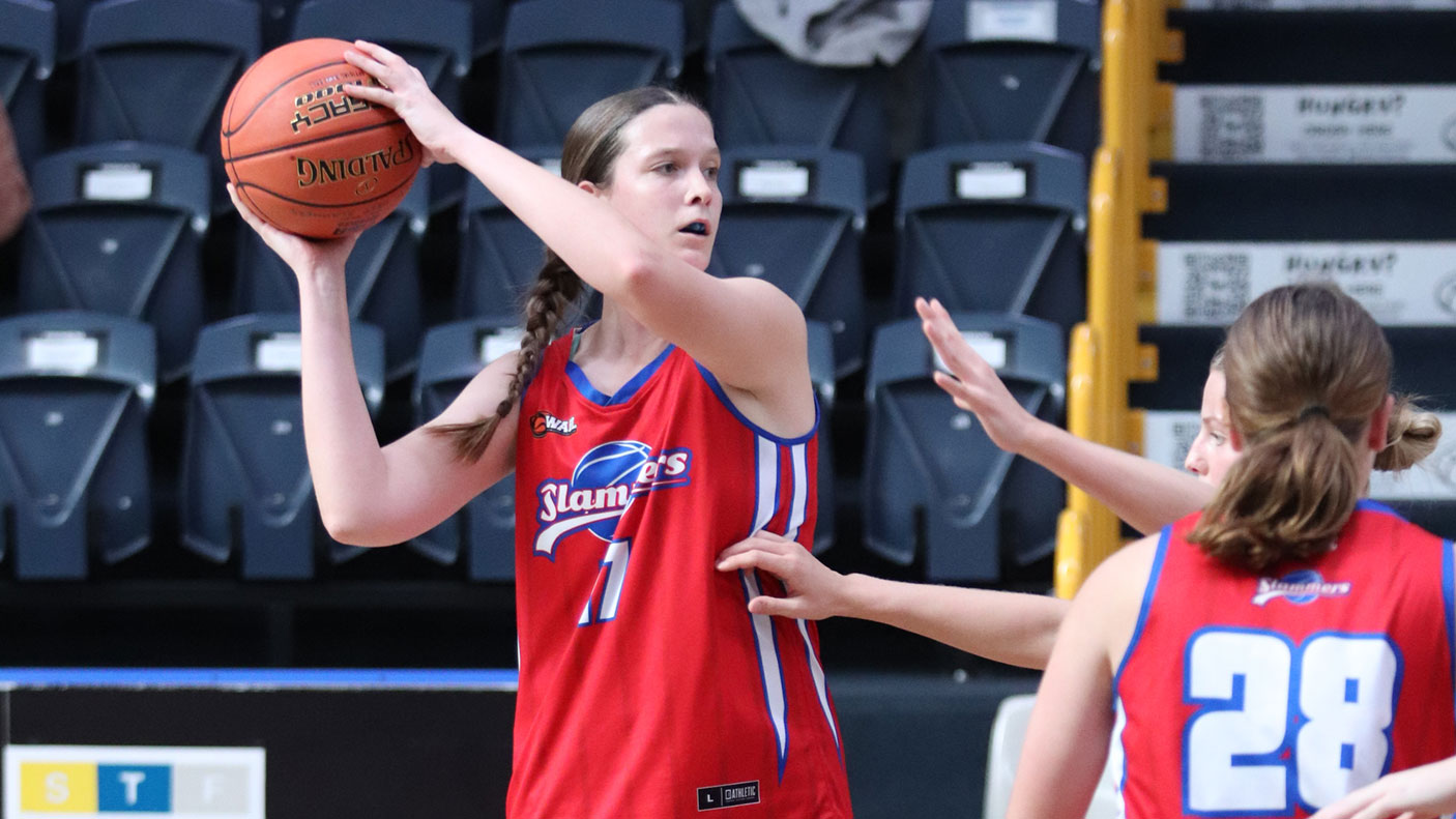 A basketball player holds up the ball, ready to throw it to another player